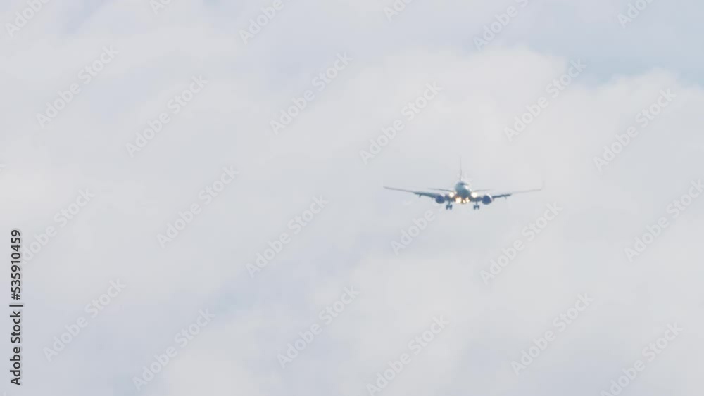 Jet airplane released landing gear. Passenger airliner landing down, front view, haze from hot weather Jet airplane released landing gear. Passenger airliner landing down, front view, haze from hot weather