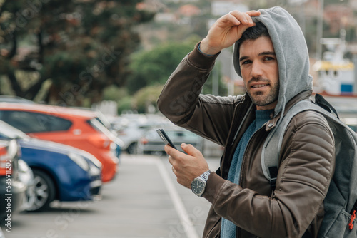 urban man with hood and backpack with mobile phone on the street