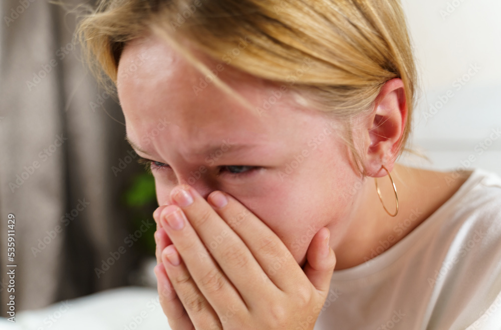 The sick girl coughs heavily, covering her mouth with her hands. The sick girl coughs heavily, covering her mouth with her hands.