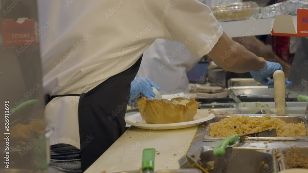 This video shows a busy Mexican restaurant kitchen with cooks assembling food like taco salads and burritos. This video shows a busy Mexican restaurant kitchen with cooks assembling food like taco salads and burritos.