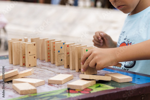 Boy playing with a wooden dominoes outside