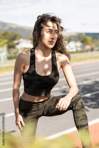 relaxed female model posing wearing sportswear, beauty and fashion of young woman with long hair moving in the wind, fitness lifestyle in park