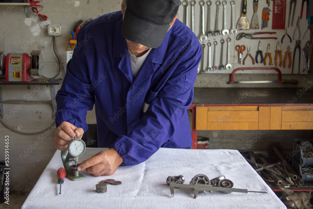 Handyman mechanic who takes precision measurements with a feeler gauge
