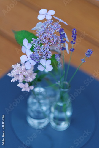 Wallpaper Mural Hortensien und Lavendel Blüten in kleine durchsichtige Flaschen auf blauem Untersetz, auf einer Holzplatte. Torontodigital.ca