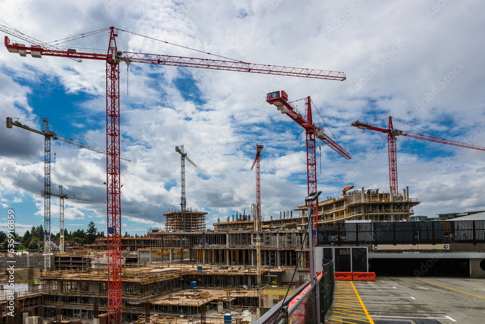 Large construction site with construction cranes working on a construction complex where foundations are laid and construction of floors of high-rise buildings has begun