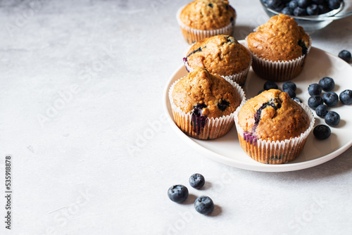 Blueberry muffins served in a plate on a marble background. Copy space.