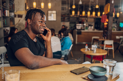 African american man using smartphone while drinking coffee in a cafe