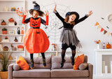 Happy Halloween. Kids girls in carnival costumes and makeup    jumping at home