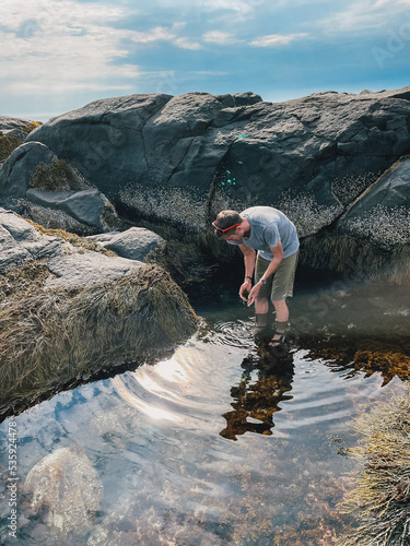 young man foraging for seaweed in a tidepool on Monhegan Island, Maine - sustainability lifestyle photo