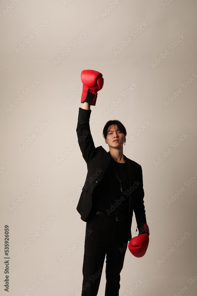 Confident young asian man with red boxer gloves posing in the studio. Winner.
