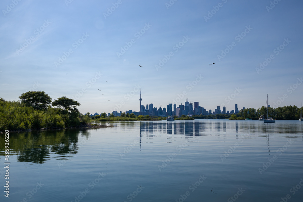 cityscape - silhouettes of skyscrapers, calm lake, forest and yacht. Blue tone
