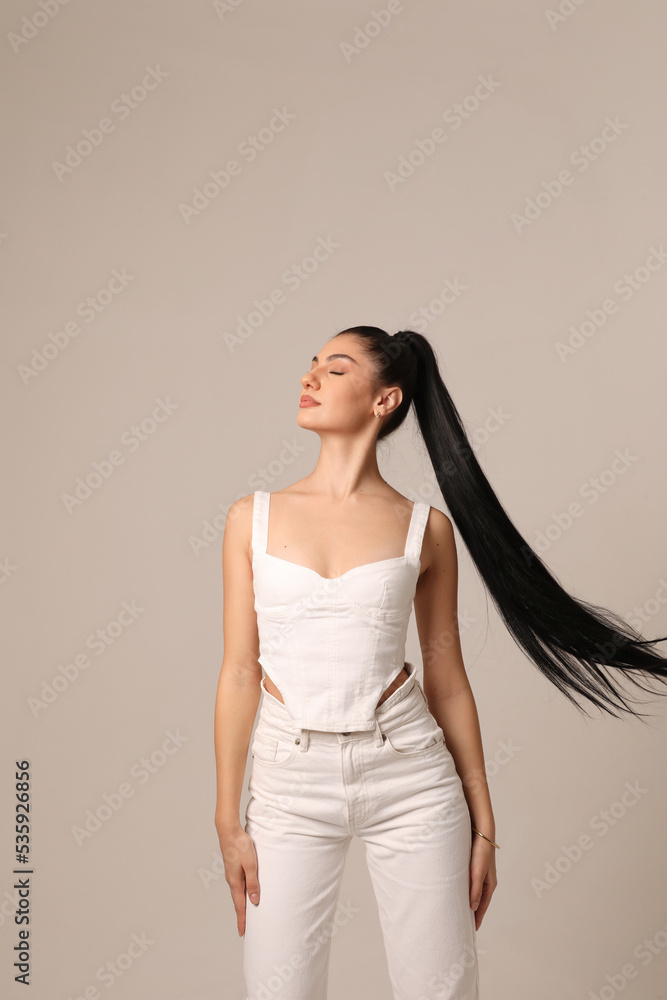 Gorgeous young woman with long dark hair dancing in the studio, over white wall. Gorgeous young woman with long dark hair dancing in the studio, over white wall.