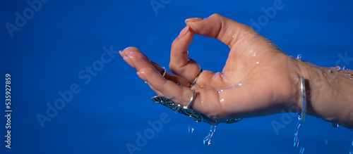 Hand of woman in mudra om in water, pool or river. Meditating in summer. Clean water . Girl calms down. Inner peace, yoga concept.