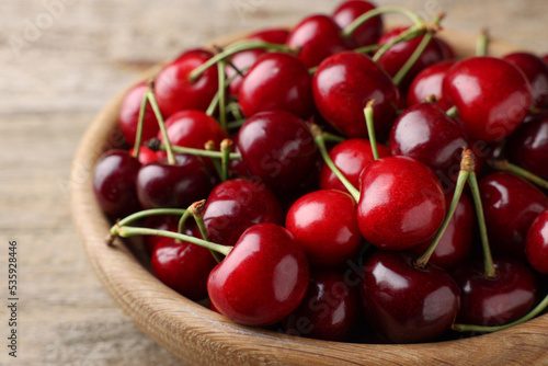 Fresh ripe cherries in wooden bowl on table, closeup