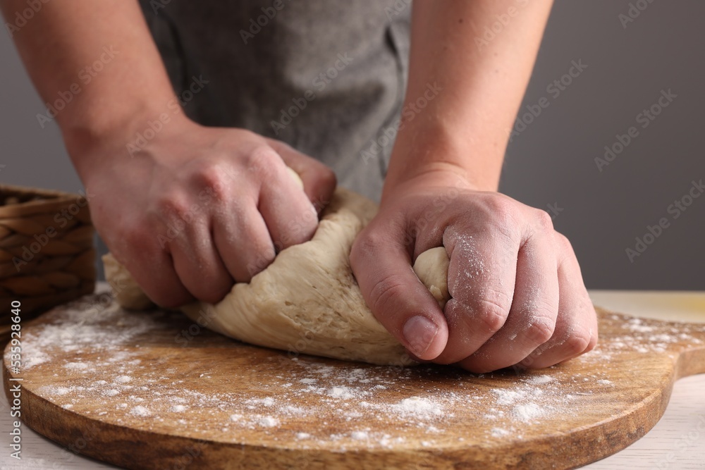 Man kneading dough at table near grey wall, closeup Man kneading dough at table near grey wall, closeup