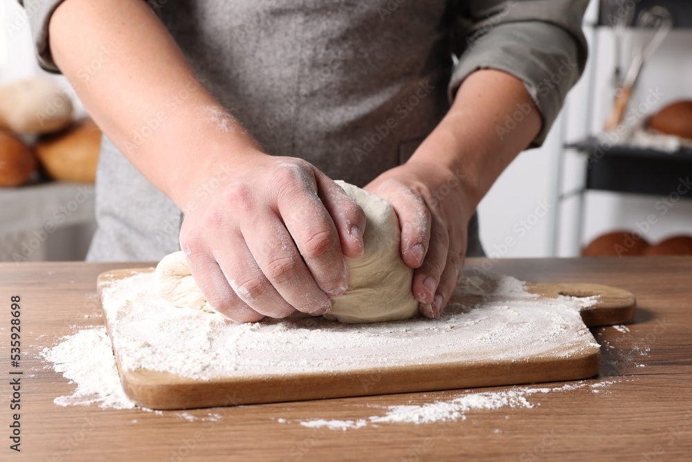 Man kneading dough at table in kitchen, closeup Man kneading dough at table in kitchen, closeup