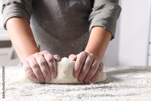 Fototapeta Naklejka Na Ścianę i Meble -  Man kneading dough at table in kitchen, closeup