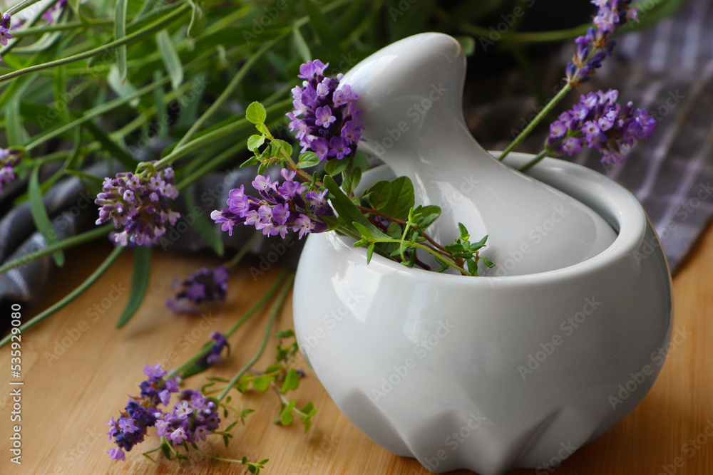 Mortar with fresh lavender flowers, green twigs and pestle on wooden table Mortar with fresh lavender flowers, green twigs and pestle on wooden table