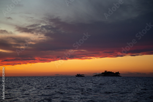 Sea panorama with a view of a small island and a ship. Sunset by the sea. Adriatic Sea