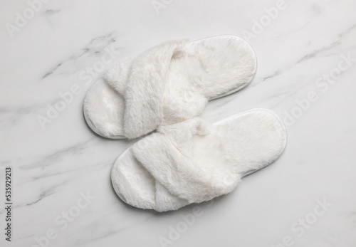 Pair of soft slippers on white marble floor, top view
