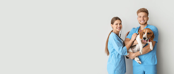 Veterinarians and cute dog on light background with space for text
