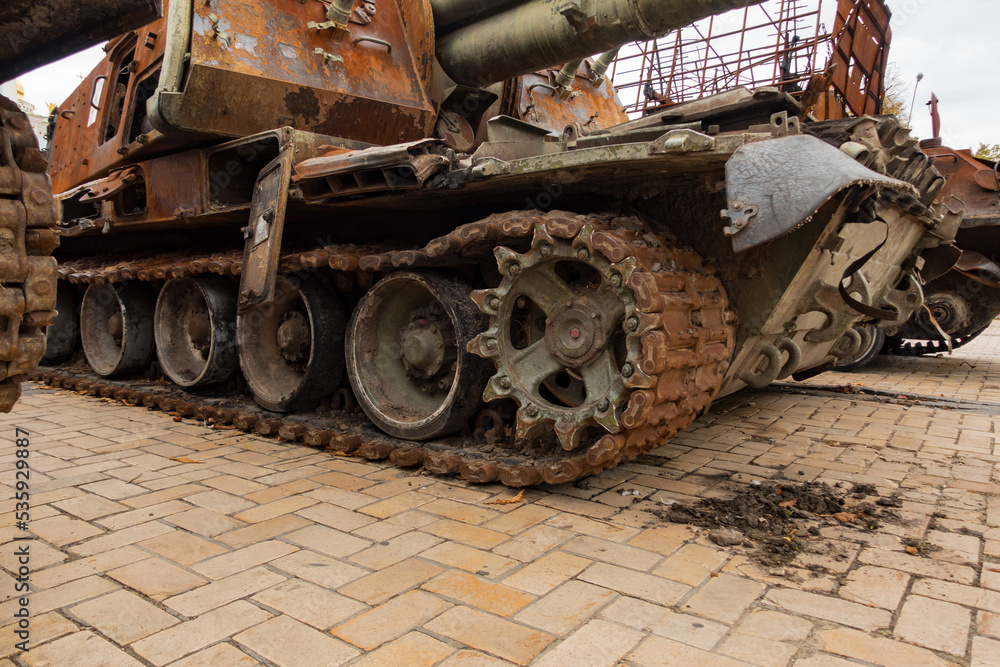 A destroyed rusty military tank stands outdoors on the street. Military. War. Ukraine. Vehicle. Weapon. Destroyed. Army. Combat. Aggression. Burnt. Invasion. Machine