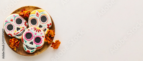 Wooden tray with tasty cookies in shape of skull for Mexico's Day of the Dead (El Dia de Muertos) on light background with space for text photo