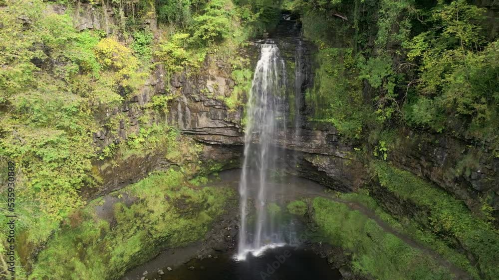 Panning camera view of a spectacular waterfall in a lush green forest