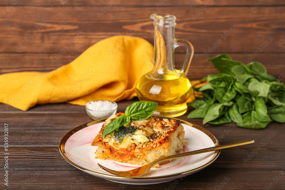 Plate of tasty Italian pie with mozzarella and pesto sauce on wooden table