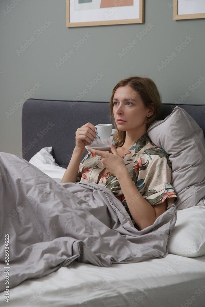 Serene woman drinking coffee in the bed, casual relaxing time alone Serene woman drinking coffee in the bed, casual relaxing time alone