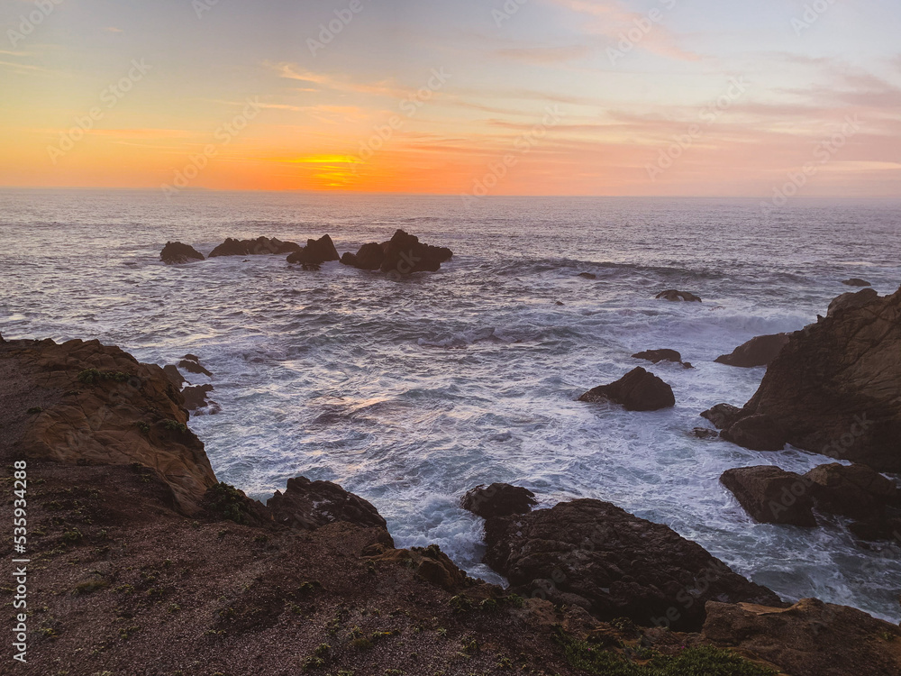 Waves crashing on rocks with sunset in Northern California 