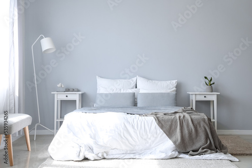 Interior of modern room with big bed, tables and lamp