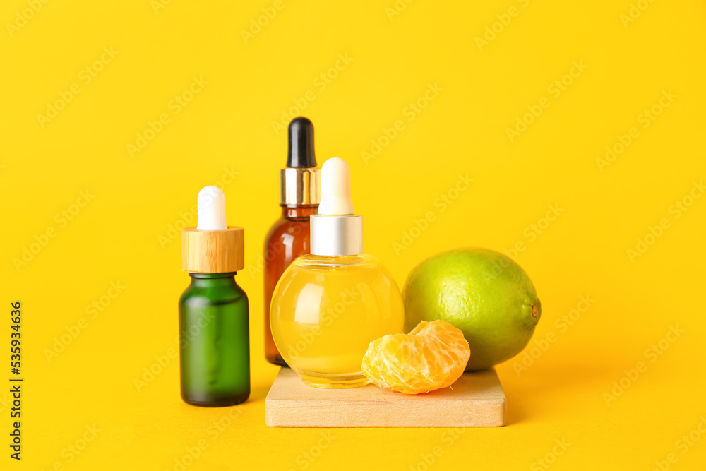 Bottles of citrus serum on yellow background Bottles of citrus serum on yellow background