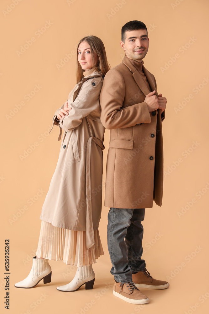Fashionable young couple in autumn clothes on beige background Fashionable young couple in autumn clothes on beige background