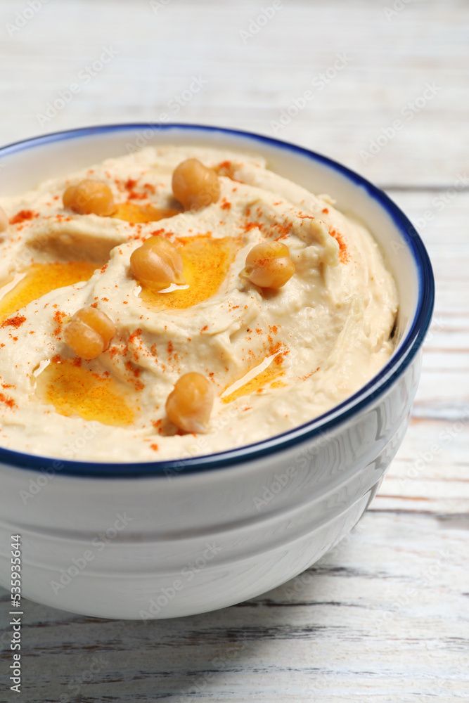 Bowl of tasty hummus with chickpeas and paprika on white wooden table, closeup Bowl of tasty hummus with chickpeas and paprika on white wooden table, closeup