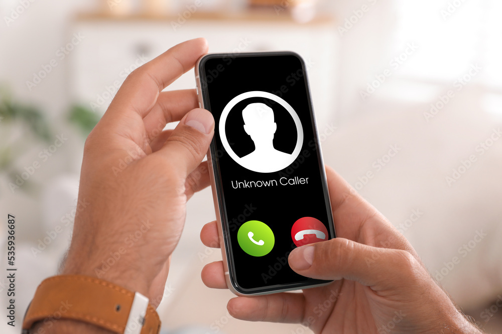 Fototapeta premium Man declining incoming call from unknown caller indoors, closeup. Be careful - fraud