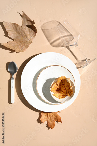 Autumn table setting with fallen leaves on beige background