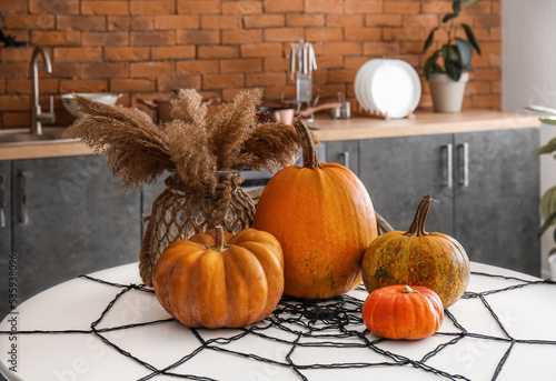 Halloween pumpkins and vase with pampas grass on dining table in kitchen