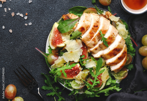 Grilled chicken fillet with fig, grape, arugula and chard salad. Black table background, top view