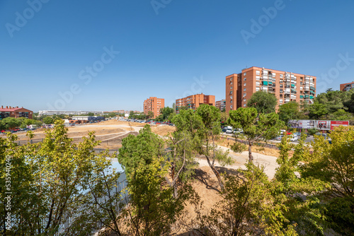 Views of the trees of an urban park and residential buildings surrounded by leafy trees in the background