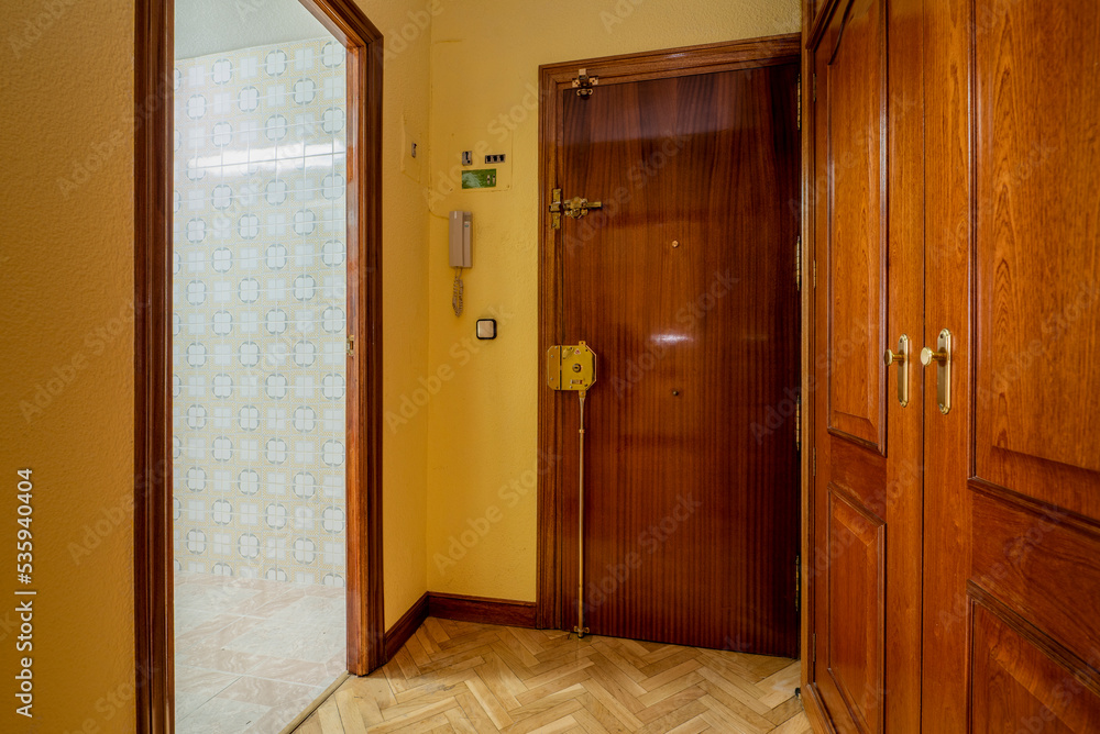 Entrance hall of an urban residential home with oak parquet flooring, mahogany cabinets and doors, and yellow painted walls Entrance hall of an urban residential home with oak parquet flooring, mahogany cabinets and doors, and yellow painted walls