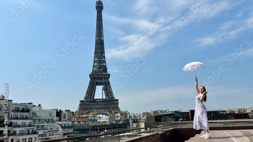 a beautiful young girl dances and spins near the Eiffel Tower with an openwork sun umbrella she is happy rejoices can be used for any advertising for any joy and happiness. High quality 4k footage