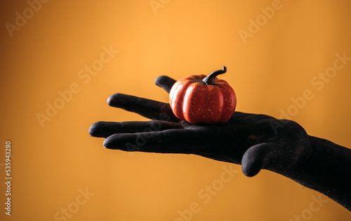 person holding a pumpkin. Black hand. Halloween concept. 