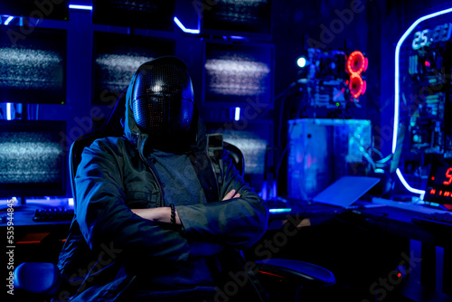 Man wear clothes look like hacker and sit with arm-crossed in room also in front of monitor show light with sign look fear and scary. Concept of safety for computor system and danger with hacker.