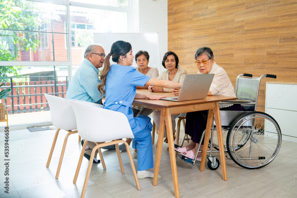 Asian senior man and woman enjoy to talk and fun with activity of nurse or doctor during teach with laptop on table in living room of clinic or hospital. Asian senior man and woman enjoy to talk and fun with activity of nurse or doctor during teach with laptop on table in living room of clinic or hospital.