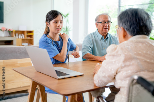 Pretty Asian young nurse or doctor explain and give consult information about shoulder pain to senior woman during discuss about health care of elderly patient.