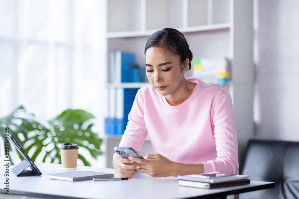 Portrait of an attractive young Asian woman holding her smartphone while working in home workplace, Business Asian woman documents and ideas. Portrait of an attractive young Asian woman holding her smartphone while working in home workplace, Business Asian woman documents and ideas.