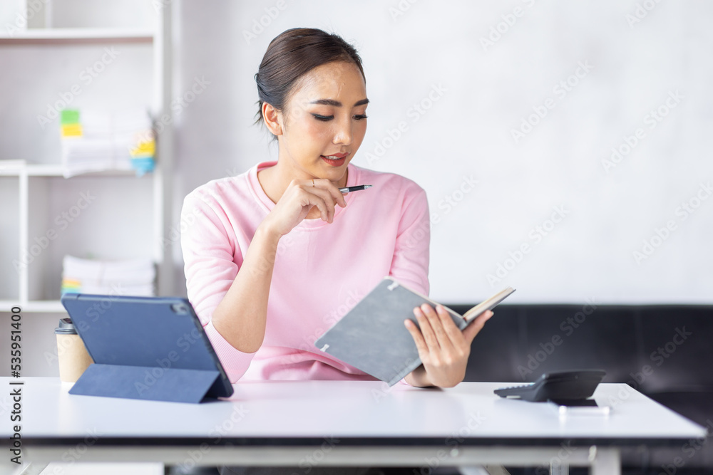 Young business Asian woman working in note and tablet the home workplace, reading and taking notes on the paper, accounting, tax, Financial, Business concept Young business Asian woman working in note and tablet the home workplace, reading and taking notes on the paper, accounting, tax, Financial, Business concept