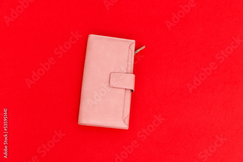 Pink leather wallet on red background