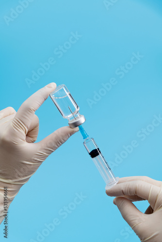 Hand holding syringe and vaccine on blue background